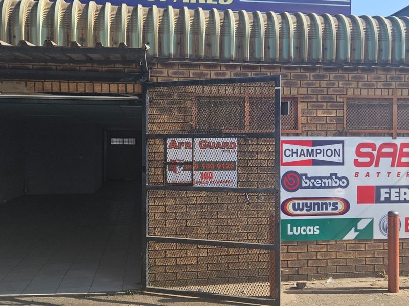 Front exterior view of a commercial property featuring a face brick facade, corrugated metal roof, and prominent signage.