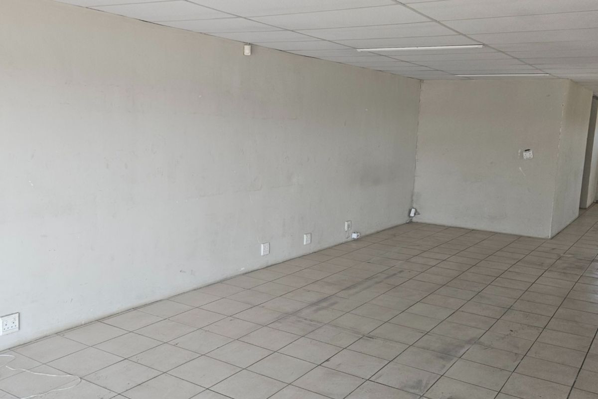 An empty, open-plan commercial office space featuring tiled flooring, a suspended ceiling, and multiple electrical power points.