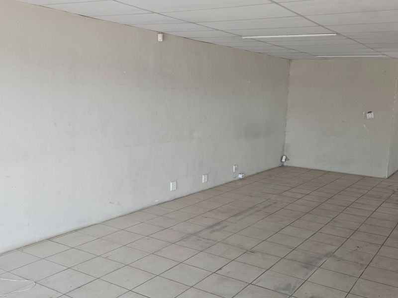 An empty, open-plan commercial office space featuring tiled flooring, a suspended ceiling, and multiple electrical power points.
