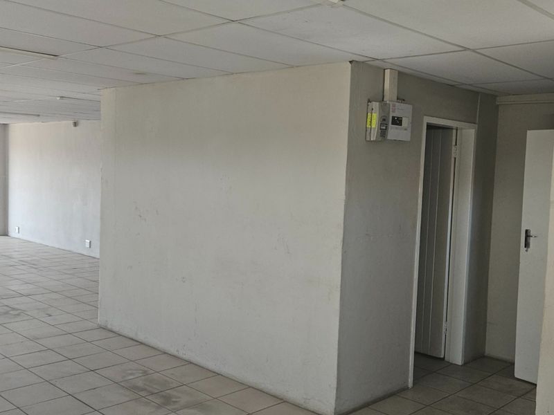 An empty, open-plan utility or commercial space featuring ceramic tiled flooring, a suspended ceiling, and an integrated electrical distribution board.