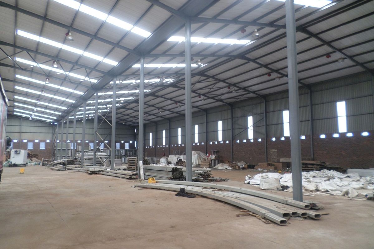 Spacious industrial warehouse featuring a high-clearance steel portal frame, corrugated metal roofing with integrated skylights, and durable concrete flooring.