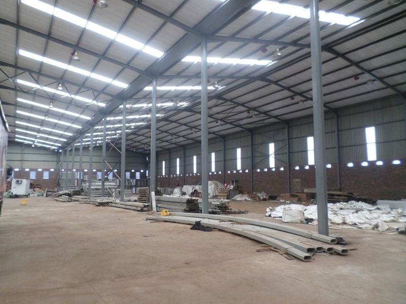 Spacious industrial warehouse featuring a high-clearance steel portal frame, corrugated metal roofing with integrated skylights, and durable concrete flooring.