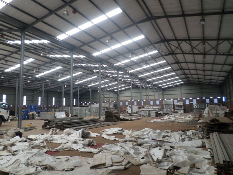 Large industrial warehouse space featuring a steel portal frame structure, high ceilings with integrated skylights, and durable concrete flooring.