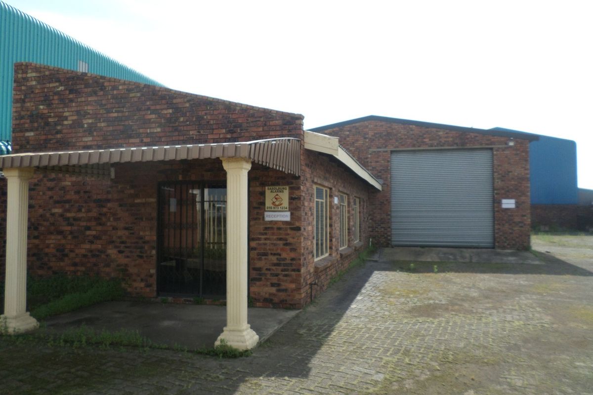 Industrial property featuring a face brick facade, a large roller shutter door for vehicle access, and a covered entrance area with paved driveway.