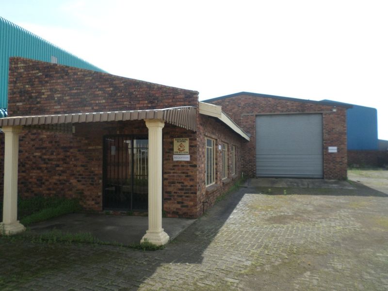 Industrial property featuring a face brick facade, a large roller shutter door for vehicle access, and a covered entrance area with paved driveway.