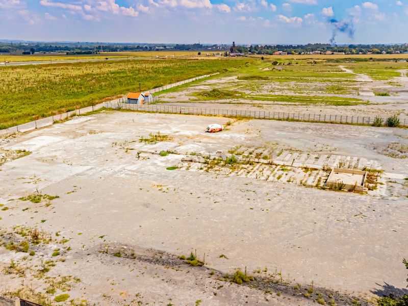 Aerial view of a large industrial plot featuring a concrete slab foundation, perimeter fencing, and expansive open land suitable for development.