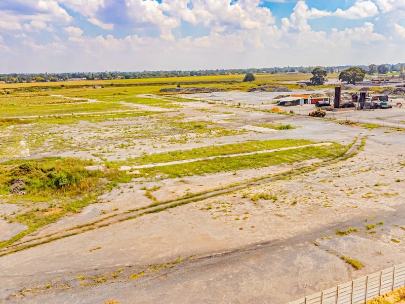 Aerial view of a large, expansive industrial plot featuring a paved yard, perimeter fencing, and existing industrial storage infrastructure.