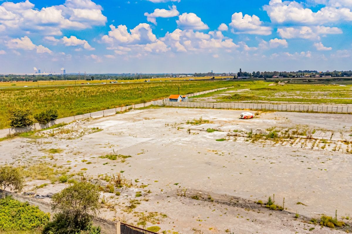 Aerial view of a large industrial plot featuring a concrete hardstand, perimeter wall, and security gate, suitable for development or storage.