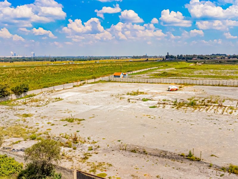 Aerial view of a large industrial plot featuring a concrete hardstand, perimeter wall, and security gate, suitable for development or storage.