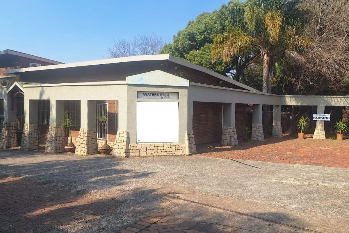 Front exterior view of the office building featuring a brick facade, stone-clad pillars, and a paved driveway area.