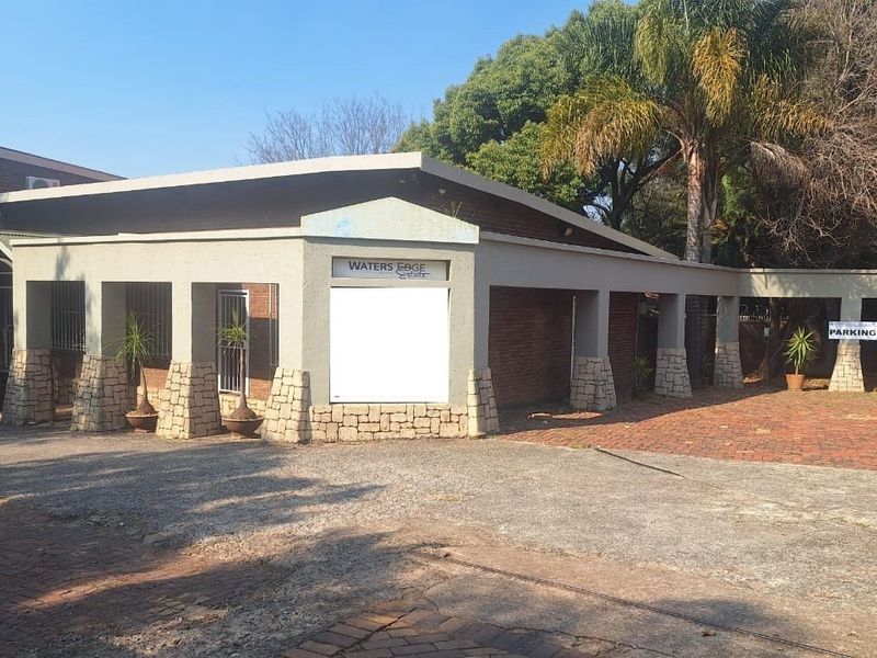 Front exterior view of the office building featuring a brick facade, stone-clad pillars, and a paved driveway area.