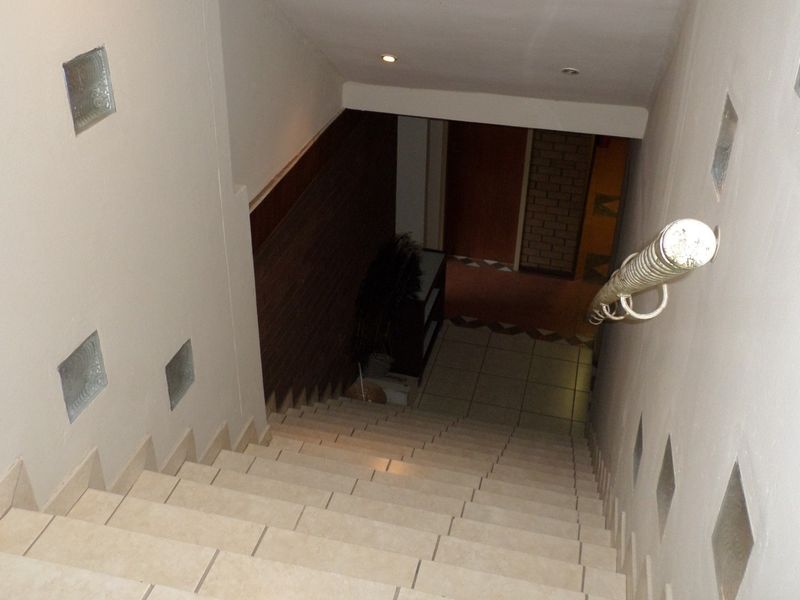 A tiled staircase featuring a metal handrail and decorative glass block wall inserts, leading down to a lower level office area.
