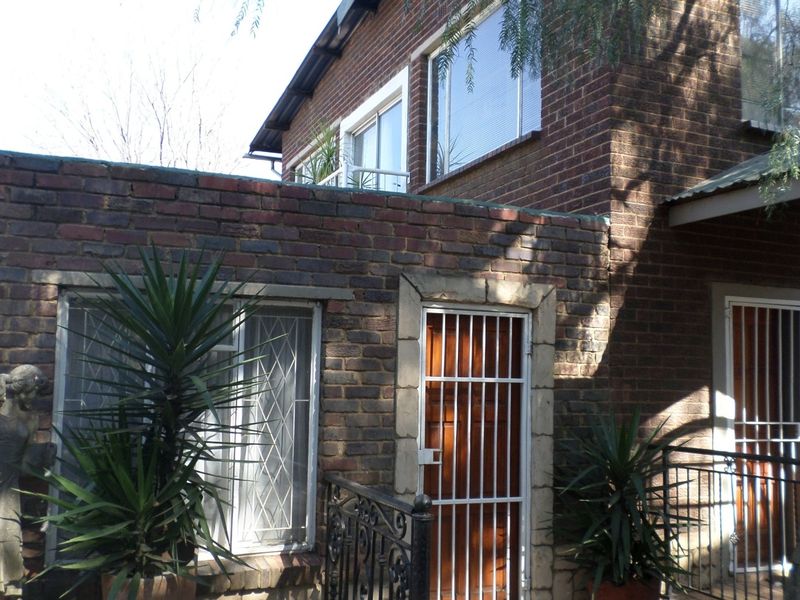Front exterior view of a double-story brick office building featuring security gates and aluminium window frames.