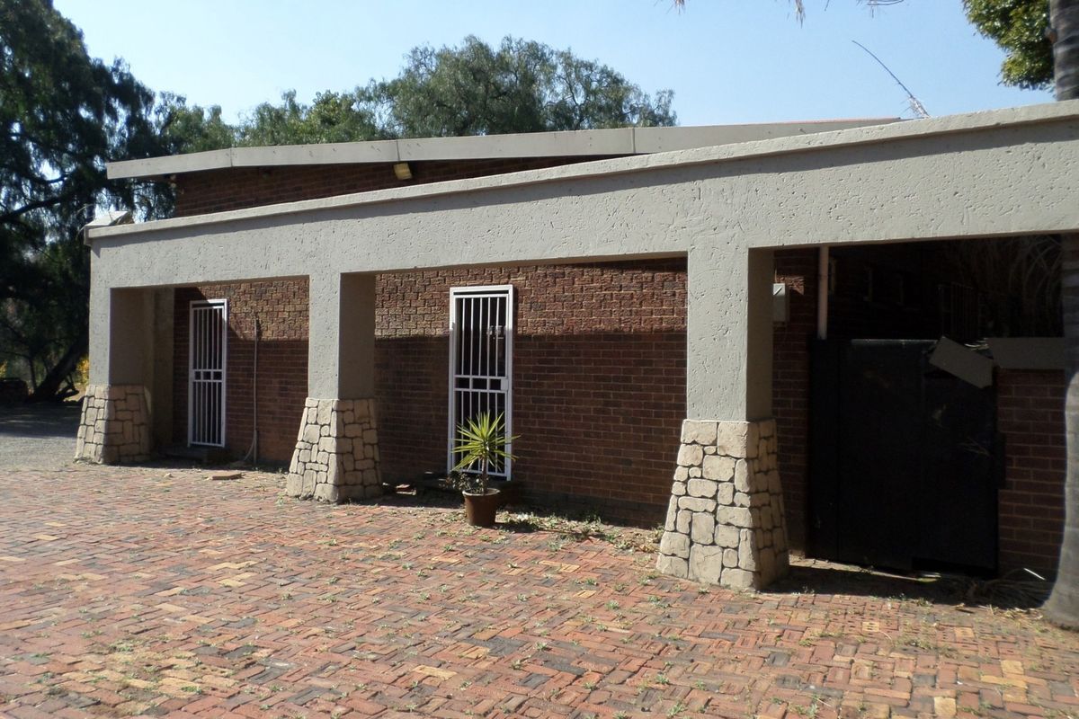 Rear exterior view of the office building featuring a brick facade, stone-clad pillars, a covered walkway, and a brick-paved courtyard area.