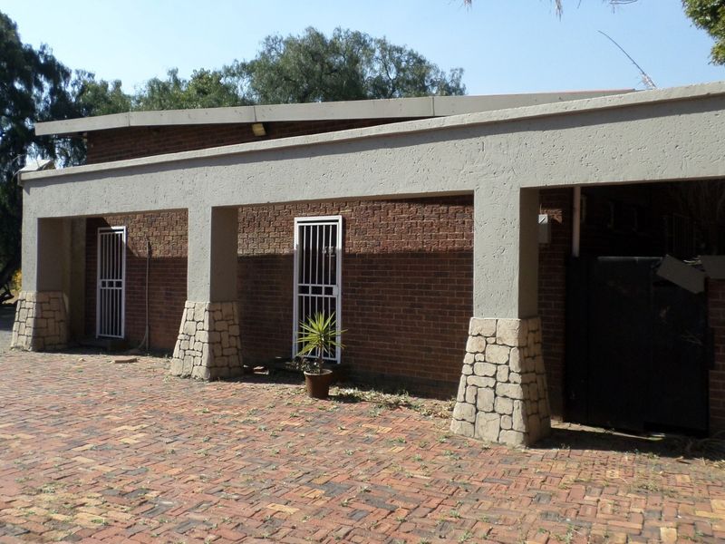 Rear exterior view of the office building featuring a brick facade, stone-clad pillars, a covered walkway, and a brick-paved courtyard area.