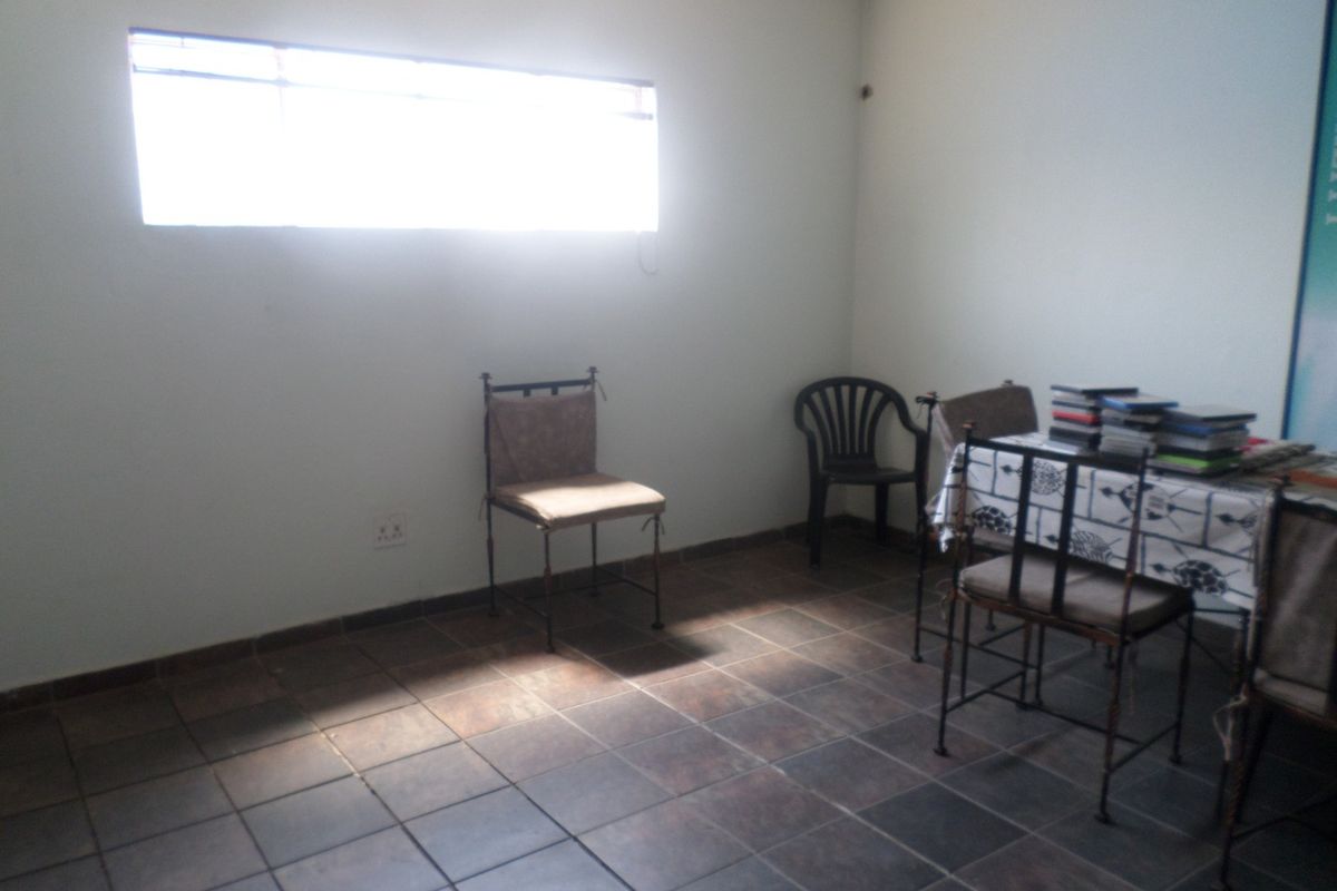 A simple living area featuring dark tiled flooring and a horizontal window, providing a functional space with neutral wall finishes.