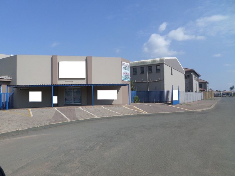 Front exterior view of a commercial property featuring a paved parking area, covered entrance canopy, and secure metal perimeter fencing.