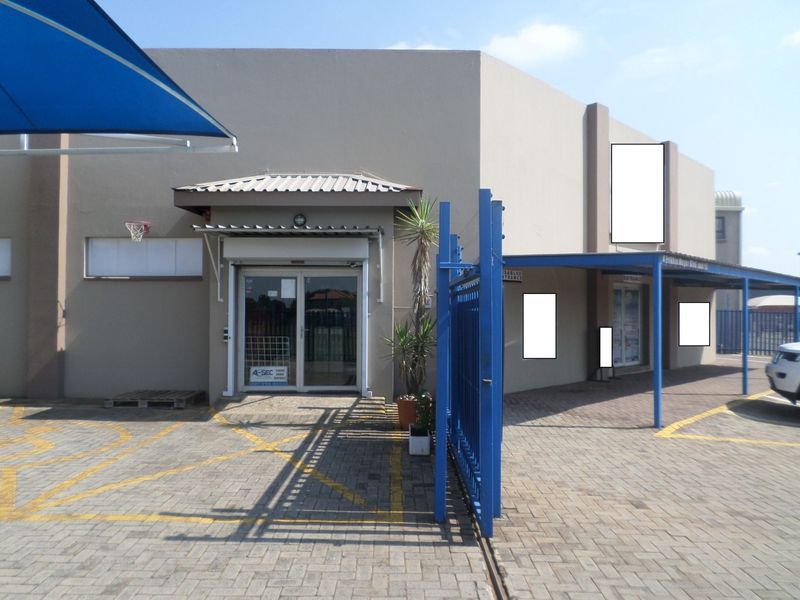 Commercial property exterior featuring a paved entrance area, security gate, and covered access point with glass doors.