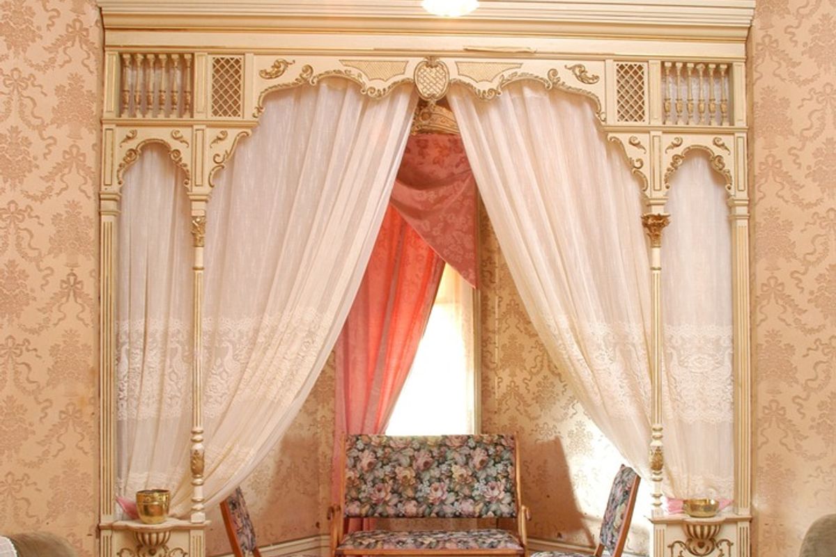 A character-filled living room featuring an ornate timber archway, decorative ceiling cornices, and original hardwood flooring, showcasing classic architectural details.