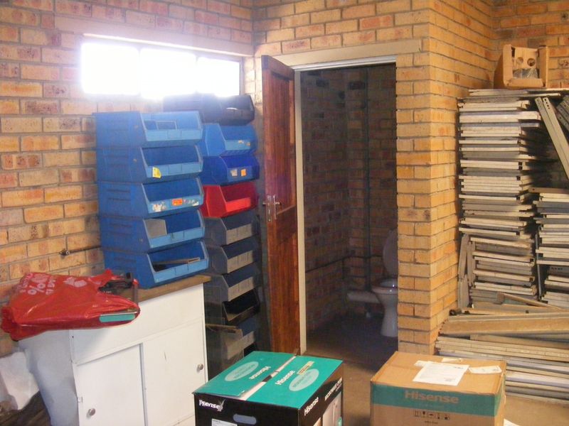 Utility space featuring exposed brick walls and a separate enclosed toilet area, suitable for storage or workshop use.