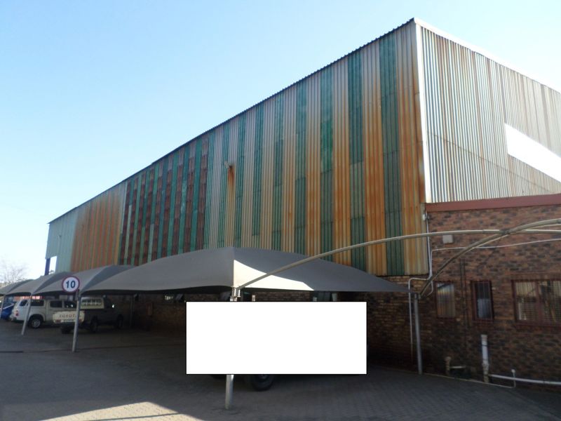 Industrial property exterior featuring a brick facade and large corrugated metal cladding with visible signs of surface rust and weathering.