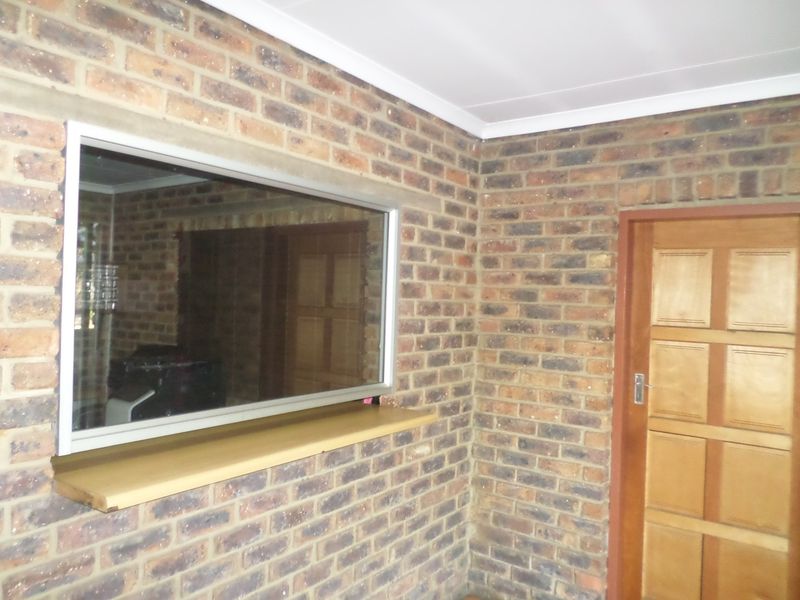 An interior utility space featuring exposed brick walls, a timber door, and an aluminium-framed window with a timber sill.