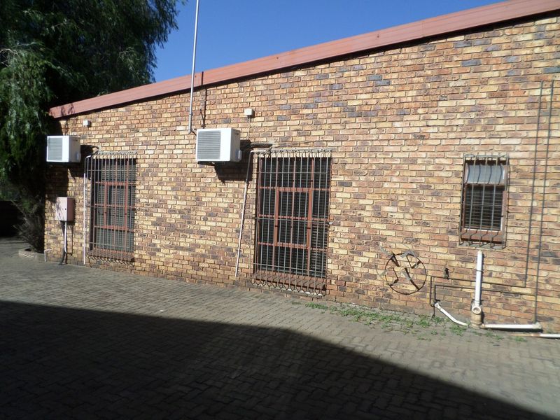 Rear exterior view of the industrial property featuring a face brick facade, security bars on windows, and external air conditioning units.