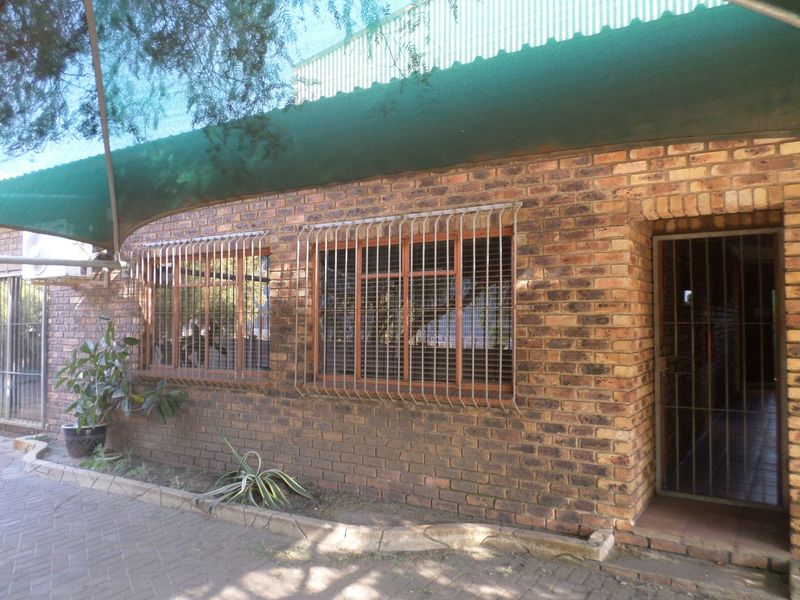 Exterior view of an industrial building featuring a face brick facade, security bars on windows, a security gate, and a shade cloth awning.