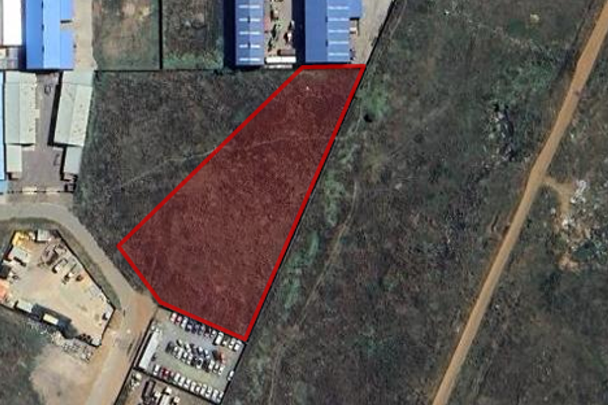 Aerial view of a vacant industrial plot outlined in red, situated within an established industrial zone.