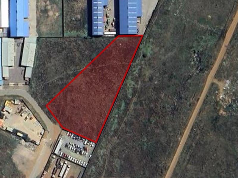 Aerial view of a vacant industrial plot outlined in red, situated within an established industrial zone.