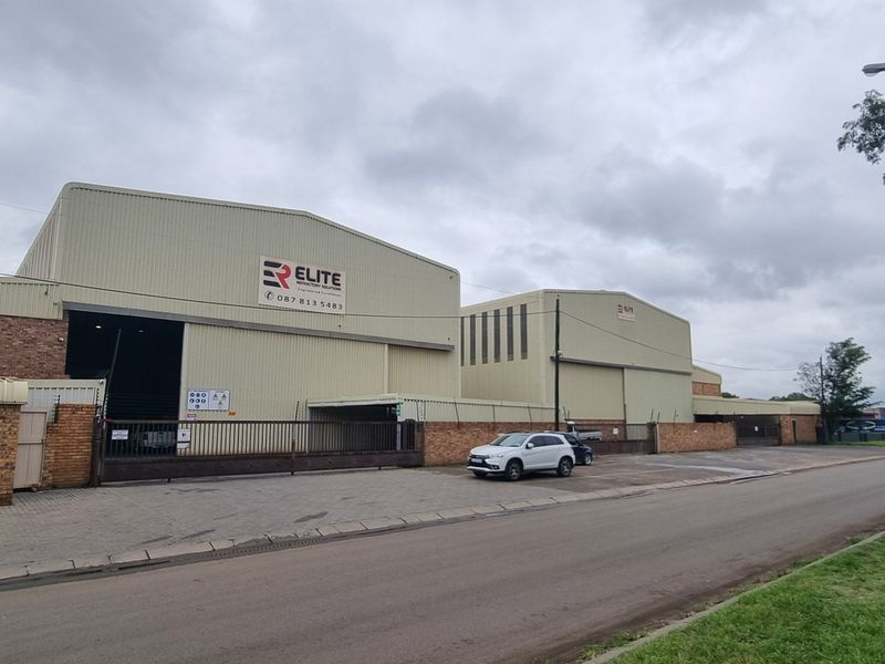 Industrial warehouse facility featuring metal cladding, secure perimeter walling, and a gated entrance, situated with direct street access.