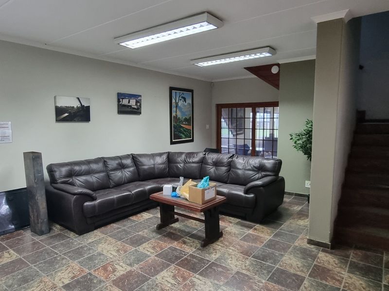 A functional living area featuring tiled flooring, fluorescent lighting, and an internal staircase, providing access to upper levels within the industrial property.