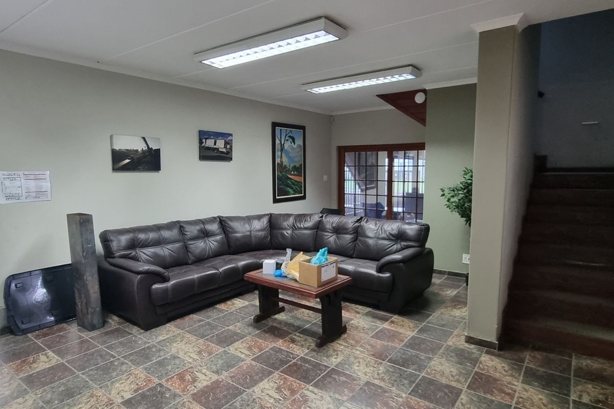 A functional living area featuring tiled flooring, fluorescent lighting, and an internal staircase, providing access to upper levels within the industrial property.