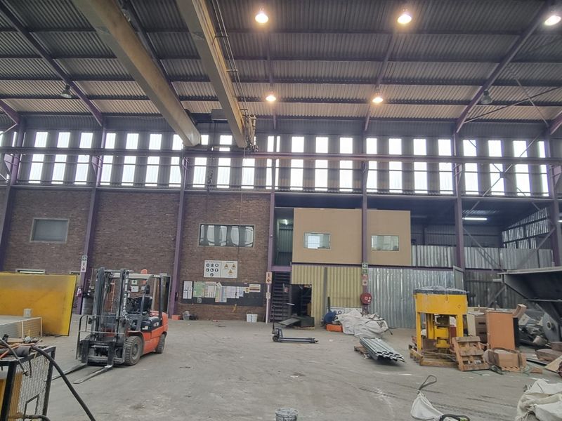 Spacious industrial warehouse featuring a high-clearance steel portal frame, clerestory windows for natural light, and an integrated mezzanine office structure.