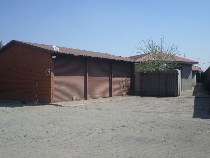 Industrial property featuring a multi-bay garage with roller shutter doors and a paved driveway area.