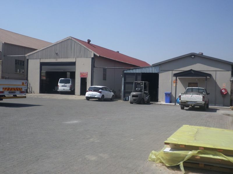 Industrial property featuring two warehouse units with roller shutter doors and a paved yard area suitable for vehicle access and logistics operations.