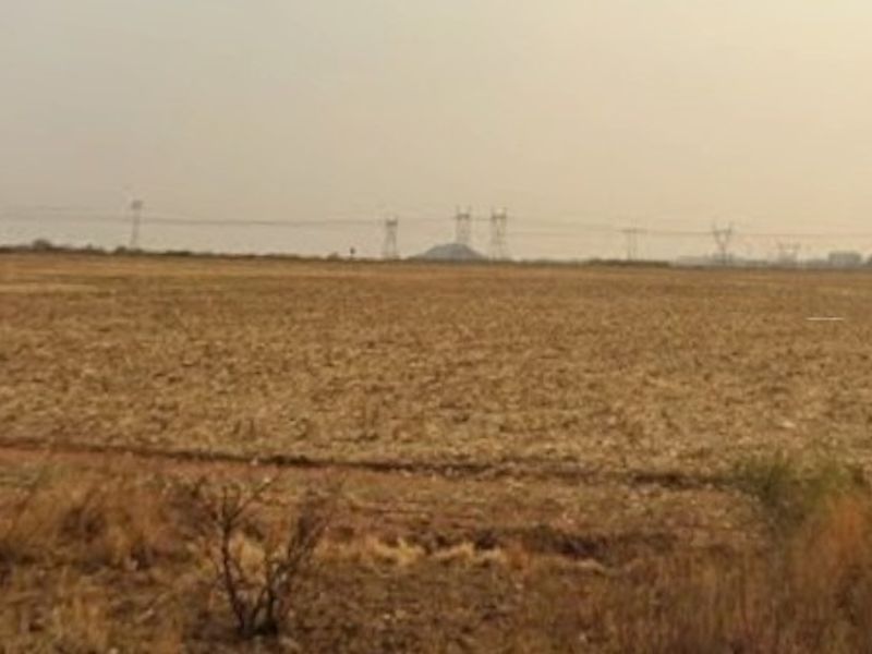 A wide-angle view of open farmland with visible power lines stretching across the horizon.