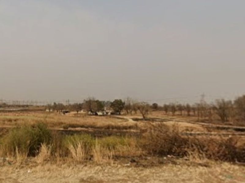 A wide landscape view of the farm property featuring open fields and natural vegetation under a hazy sky.