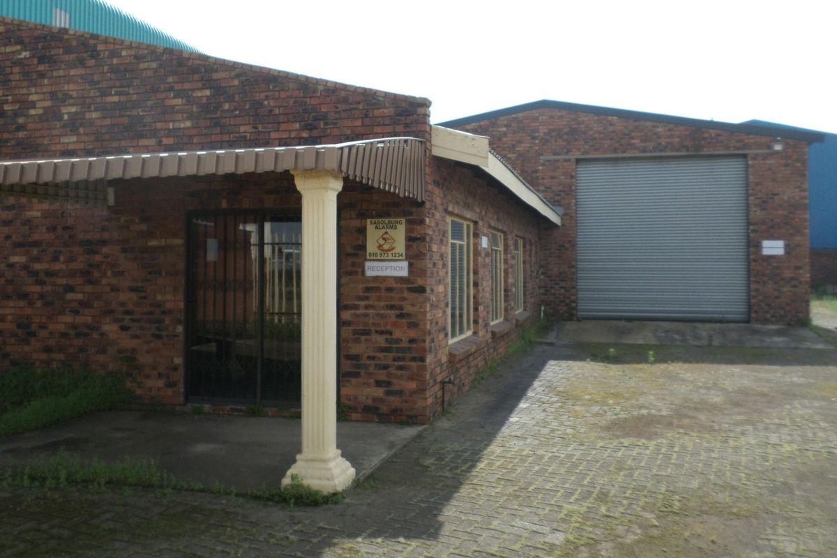 Industrial property featuring a face brick facade, a large roller shutter door for vehicle access, and a covered entrance area with paved driveway.