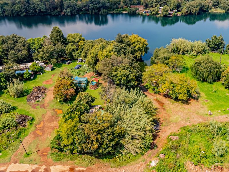 Aerial view of a large, undeveloped commercial land parcel featuring extensive river frontage, mature trees, and natural vegetation.