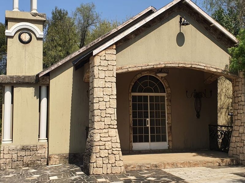 Front facade of a commercial building featuring stone-clad pillars, an arched entrance, and a decorative clock tower.