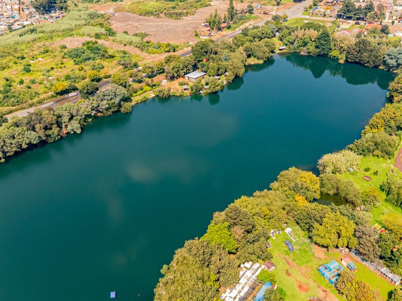 An aerial view of a large lake surrounded by mature trees and landscaped grounds, showcasing the natural setting of the property.