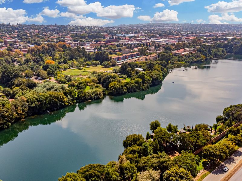 An expansive aerial view showcasing a large lake surrounded by lush greenery and the surrounding urban landscape.