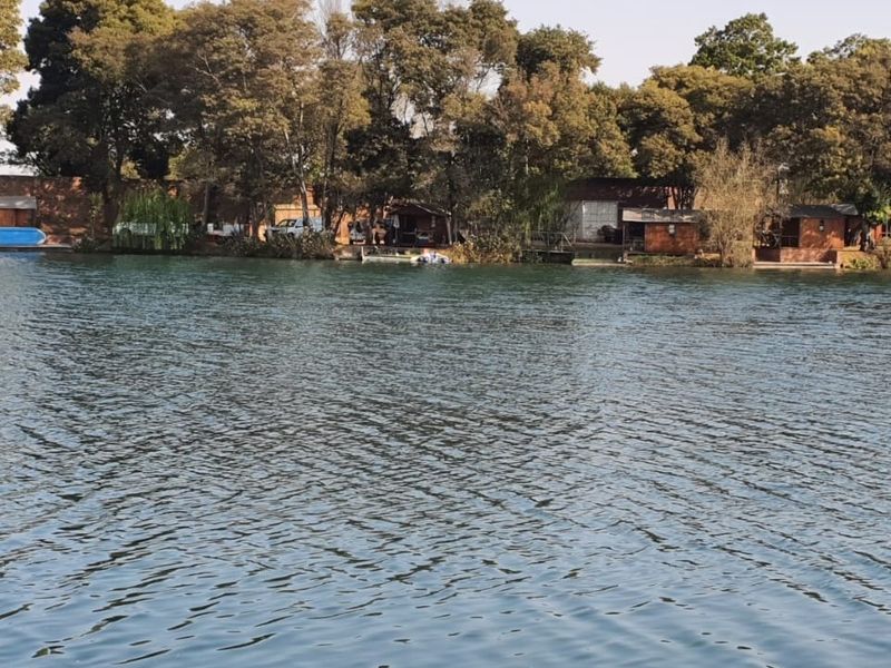 A scenic view of the property's waterfront, featuring mature trees and established structures along the bank.