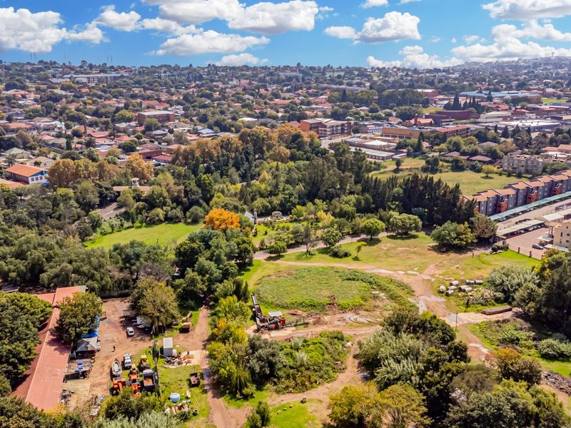 Aerial view of the property grounds featuring extensive green space, mature trees, and surrounding urban infrastructure.