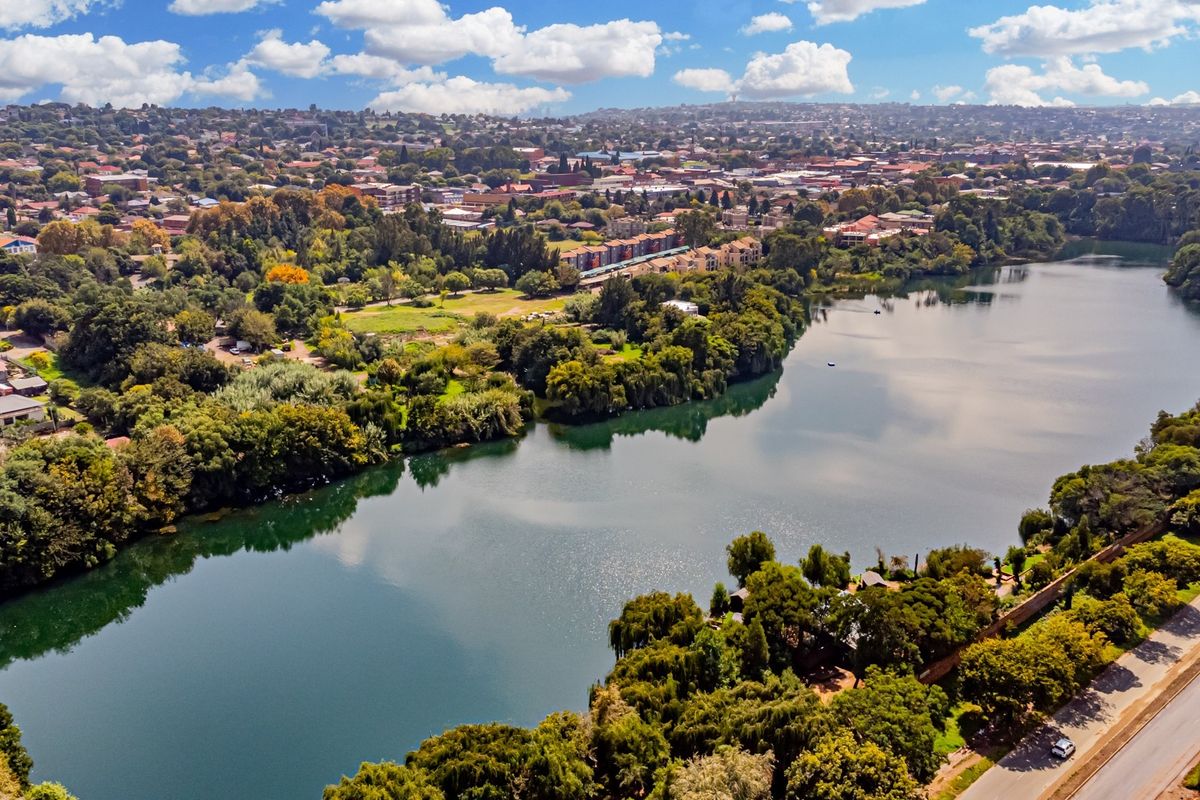 An expansive aerial view showcasing a large lake surrounded by lush greenery and the surrounding urban landscape.