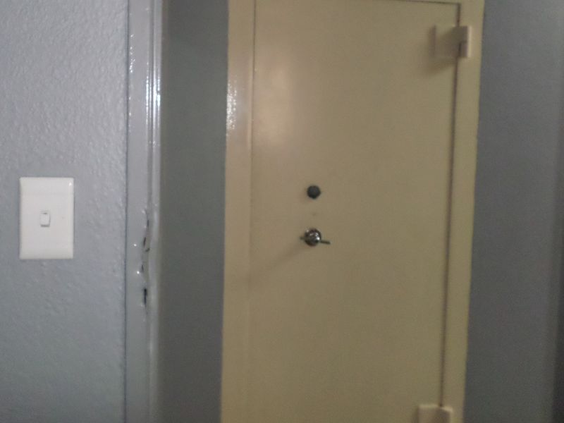 A utility space featuring a built-in wall safe and a light switch, showing signs of wear on the door frame.