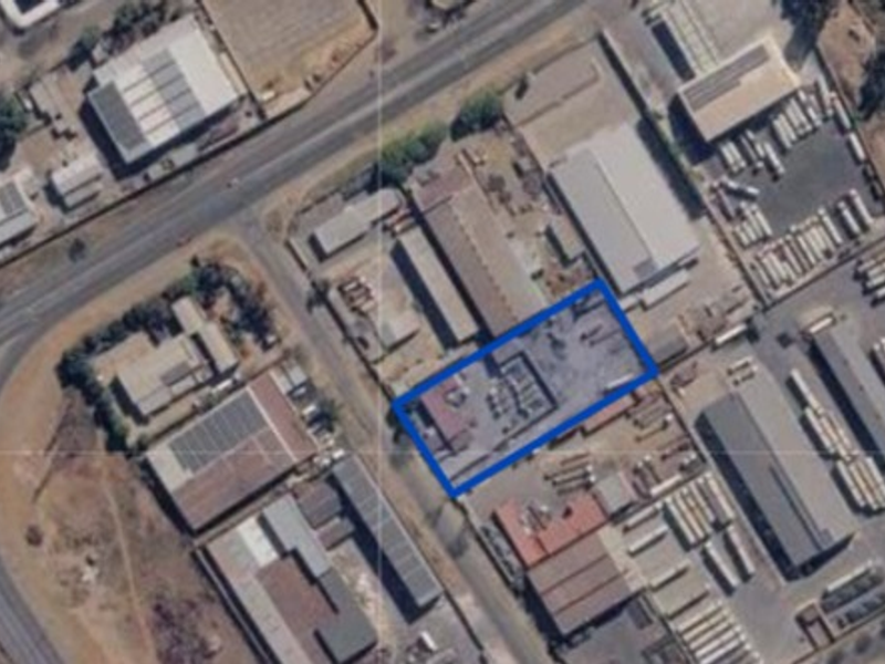 Aerial view of an industrial property featuring a warehouse building and paved yard space within a commercial industrial park setting.