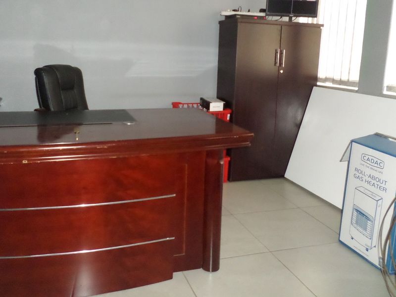 A functional office space featuring tiled flooring and vertical window blinds, providing a practical environment for professional use.
