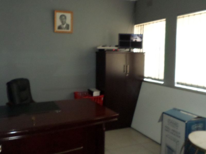 A functional office space featuring tiled flooring and vertical window blinds, providing a practical environment for professional use.